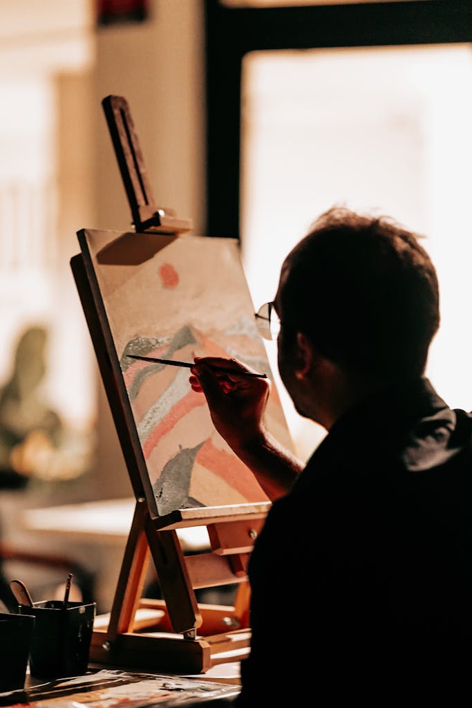 A male artist concentrating intently as he paints an abstract piece indoors in Ankara, Türkiye.