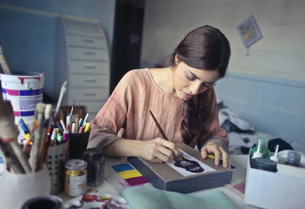 Female artist deeply engaged in painting at her creative studio workspace.
